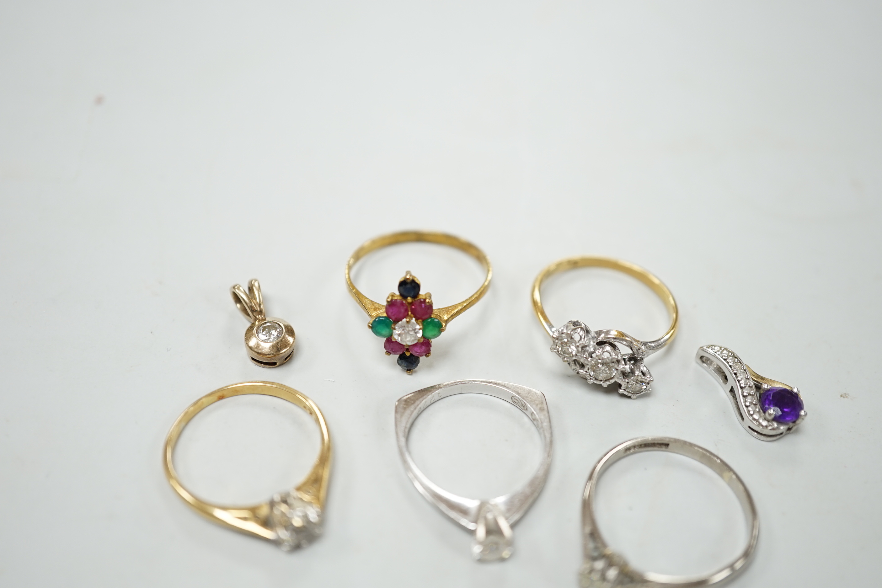 Three assorted 18ct and solitaire diamond set rings, an 18ct and illusion set three stone diamond crossover ring and an 18k and gem set cluster ring, gross weight 10.9 grams, three modern gem set small pendants and a dia